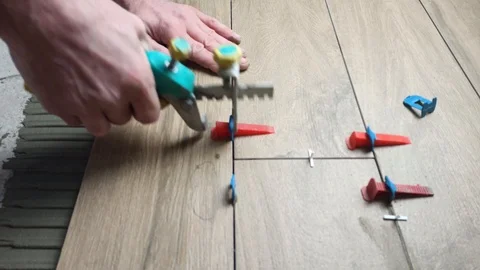 Tiler aligns the tile with the help of leveling tile system Stock Footage 124226996