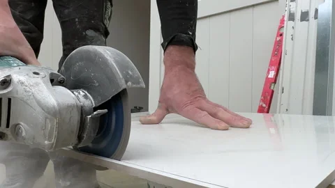 A tiler cuts ceramic tiles with a grinder. Stock-Footage 273698929