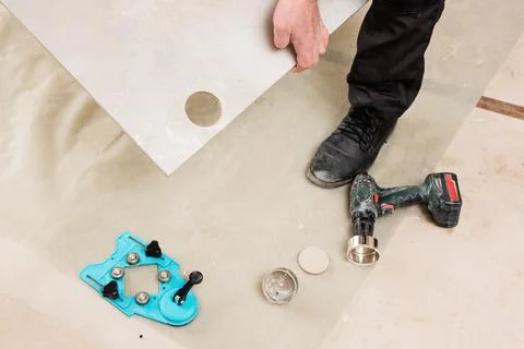 A tiler is holding a tile with a hole for a socket. Stock Photos