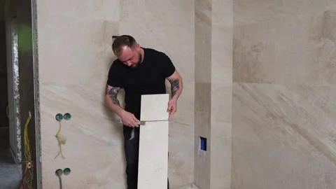 Tiler installing large format tile on bathroom wall using suction cup Stock Footage 345681386
