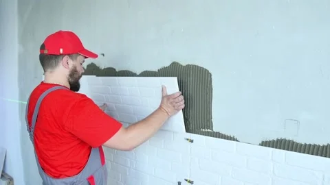 Tiler installing large size tile on wall. home indoors renovation Stock Footage 131397185
