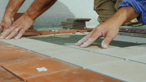 Tiler installs square tiles on floor with mortar using notched trowel profe.. Stock Footage 335057600