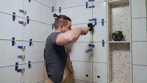 Tiler knocks the wedges of the ceramic tile leveling system off the wall in the Stock Footage 195517881