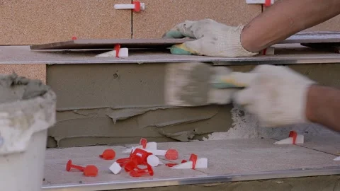 The tiler lays the floor tiles. The master skillfully owns a trowel. Stock Footage 246013377