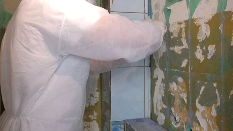 Tiler making renovation, removing tiles from wall in toilet using tool spatula. Stock-Footage 129430000
