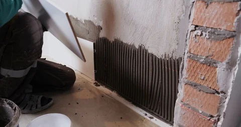 Tiler manually glues ceramic tiles to bathroom wall, taps with palm for gluing Stock Footage 129840173