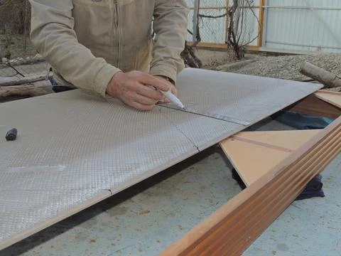 A tiler marks the material with a ruler and a marker Stock Photos