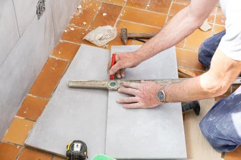 The tiler measures the tile before cutting it Stock Photos