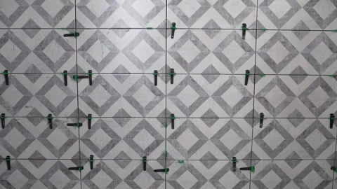 Tiler placing tiles on wall with leveling system Stock Footage 312647195