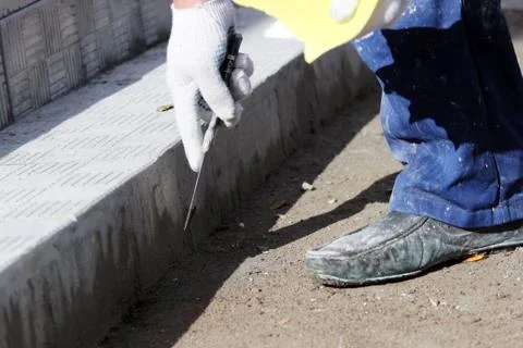 Tiler processes the surface for laying the stone tiles on the steps in the Stock Photos