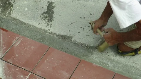 Tiler restoring sidewalk laying of tile in construction Stock Footage 101402618