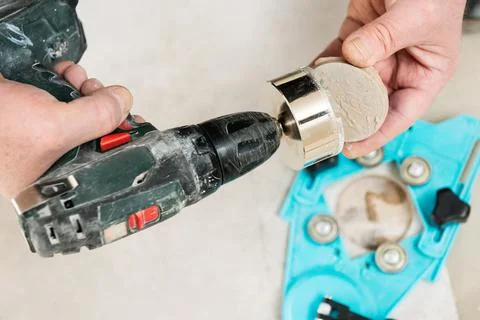 A tiler is using a diamond crown to drill holes in the ceramic tile. Stock Photos