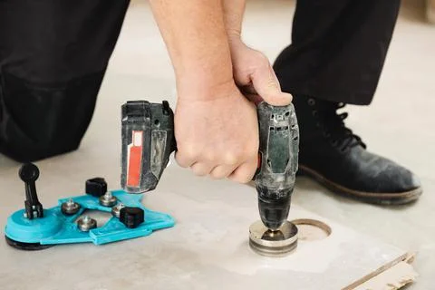 A tiler is using a diamond crown to drill holes in the ceramic tile. Stock Photos