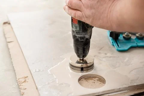 A tiler is using a diamond crown to drill holes in the ceramic tile. Stock Photos