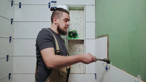 Tiler using tile leveling system when laying ceramic tiles on bathroom wall Video stock 195519042