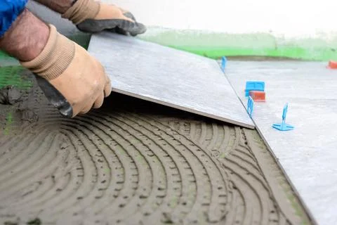 Tiler at work installing new floor with tiles. Construction. Stock Photos