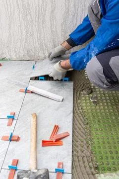 Tiler at work installing new floor with tiles. Construction. Foto stock