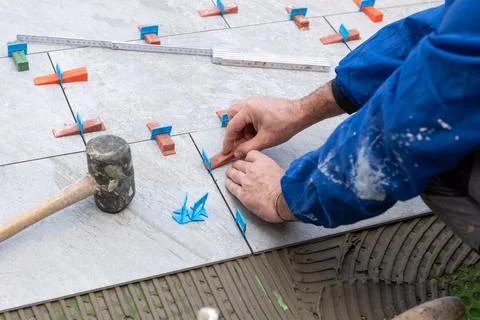 Tiler at work installing new floor with tiles. Construction. Stock Photos