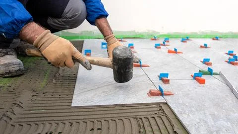 Tiler at work with rubber tile hammer. Construction. Foto stock