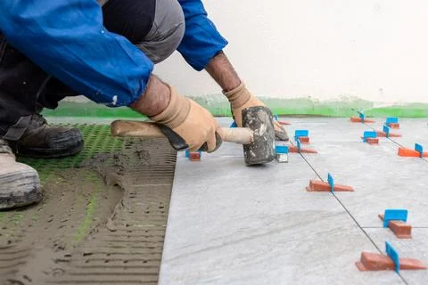 Tiler at work with rubber tile hammer. Construction. Stock Photos