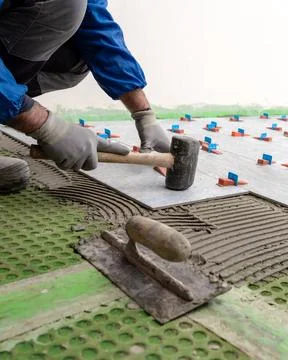 Tiler at work with rubber tile hammer. Construction. Stock-Fotos