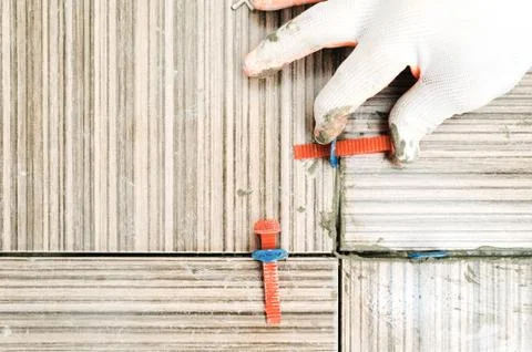 Tiler's hand is aligning tiles. Stock Photos