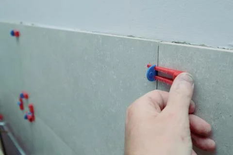 Tiler's hand installing leveling system tiles. Leveling system wedges for t.. Stock Photos