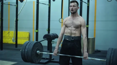 Tilt up and down of strong young aged man lifting barbell with heavy plates. Stock Footage 131331259