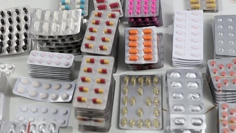 Tilt and pan shot over desk full of pills in their blisters Stock Footage 123479153