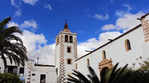 Tilt from bell tower against bright blue skies to square outside historic church Stock Footage 85301459