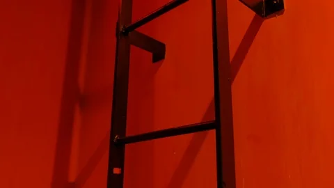 Tilt up on black ladder in red hallway Stock Footage 116689341