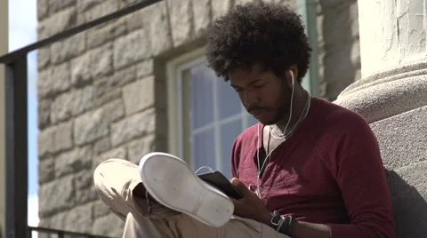 A tilt to a black student using phone on steps. Stock-Footage 44117299
