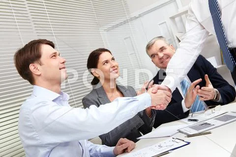 Tilt-up of business people giving a handshake to conclude the deal Stock Photos