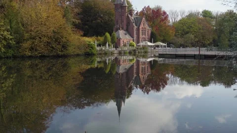 Tilt up from Castle reflection on lake on sunny fall day in Bruges, Belgium Stock Footage 329053855