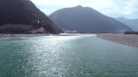 Tilt from clear river water to a backlit Tibetan mountain valley Stock Footage 345884340