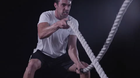 Tilt up to a closeup of a man's face working out with Battle Ropes Stock Footage 63808699