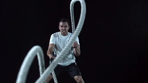 Tilt up to a closeup of a man's face working out with Battle Ropes Stock Footage 63824146