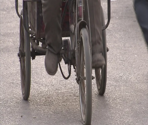 Tilt up to CU elderly man riding three wheeled cargo bicycle Stock Footage 86745477