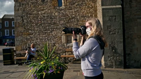 TILT DOWN from ancient stone building to reveal a young female wearing a PPE Vídeos de archivo 151695327