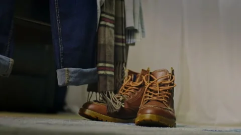 Tilt down of autumn fall clothes and boots outfit on the edge of a bed Stock Footage 204046829