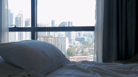 Tilt down of a bed with pillows and a modern city with tall buildings Stock Footage 86660375