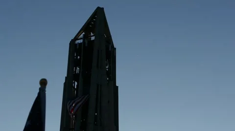 Tilt down bell tower to American flags at sunset on Veterans Day Stock Footage 56980697