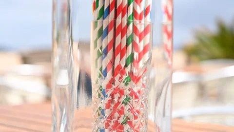 Tilt down of gin bottle biodegradable straws in a glass, beach bar background Stock Footage 109420755