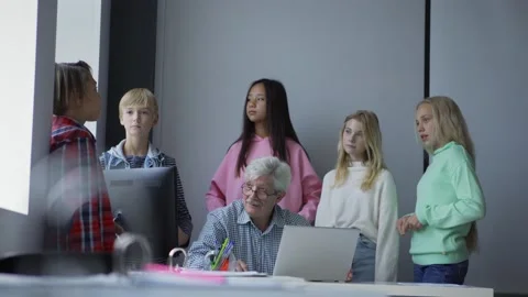 Tilt down of group of schoolchildren standing around aged male teacher with l Stock Footage 142499990