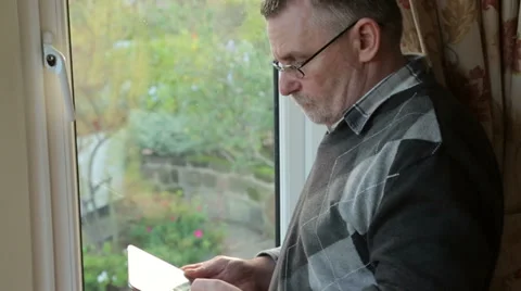 Tilt down to hands of middle aged man at home using tablet Stock Footage 33212740