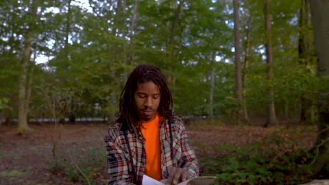 Tilt Down to Man in Park Reading Book By Himself Video stock 142012852