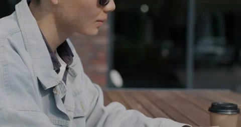 Tilt-down portrait of young Asian man using laptop typing sitting in outdoor Stock Footage 256774996