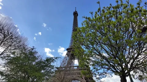 Tilt-Down Reveal of Eiffel Tower Framed by Green Spring Trees Vídeos de archivo 332602127