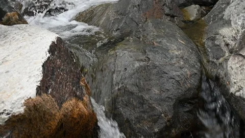 Tilt down rocky mountain stream into twin waterfall and sedimentary rock Video stock 234739049