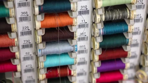 Tilt down shot of board with numbered colourful cotton thread bobbins in Stock Footage 255438951